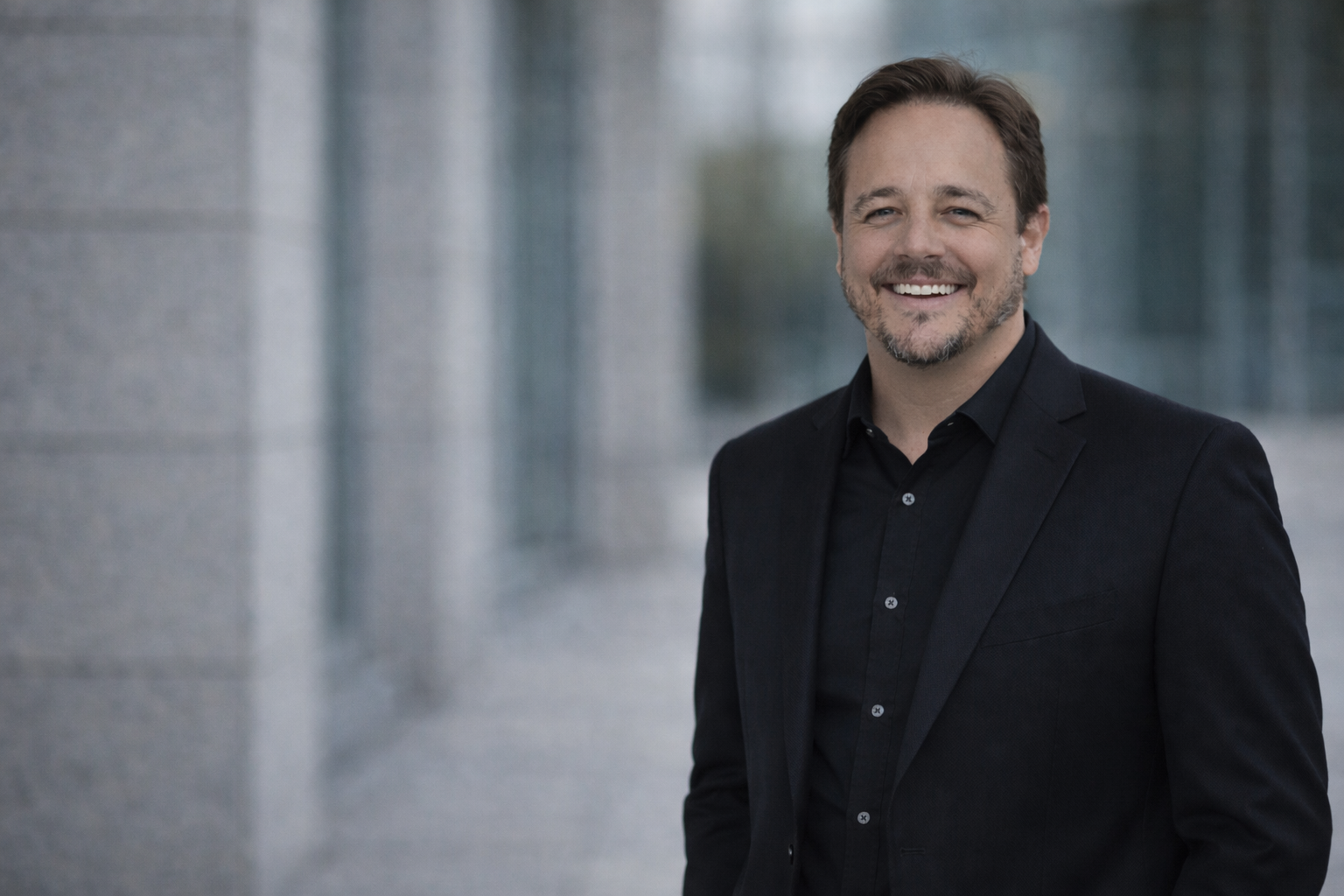 Dave Morris in a black suit, smiling